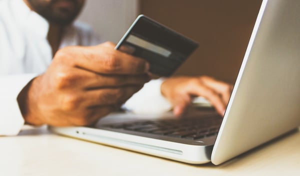 Un homme avec un ordinateur portable et une carte de crédit sort pour faire un achat.
